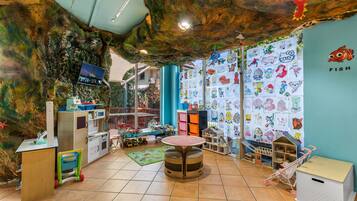 A children's playroom with a rock wall, colorful drawings, and various play furniture.