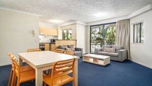 A modern living room with a dining area, a grey sofa, and a kitchen in the background. - Turtle Beach Resort (Mermaid Beach)