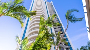 A tall, cylindrical hotel with multiple balconies and a clear blue sky. - Aegean Apartments (Surfers Paradise)