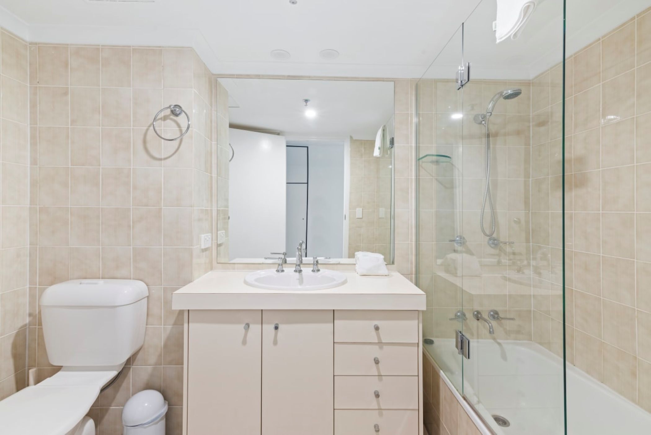 A modern bathroom with a toilet, sink, and glass-enclosed shower area.