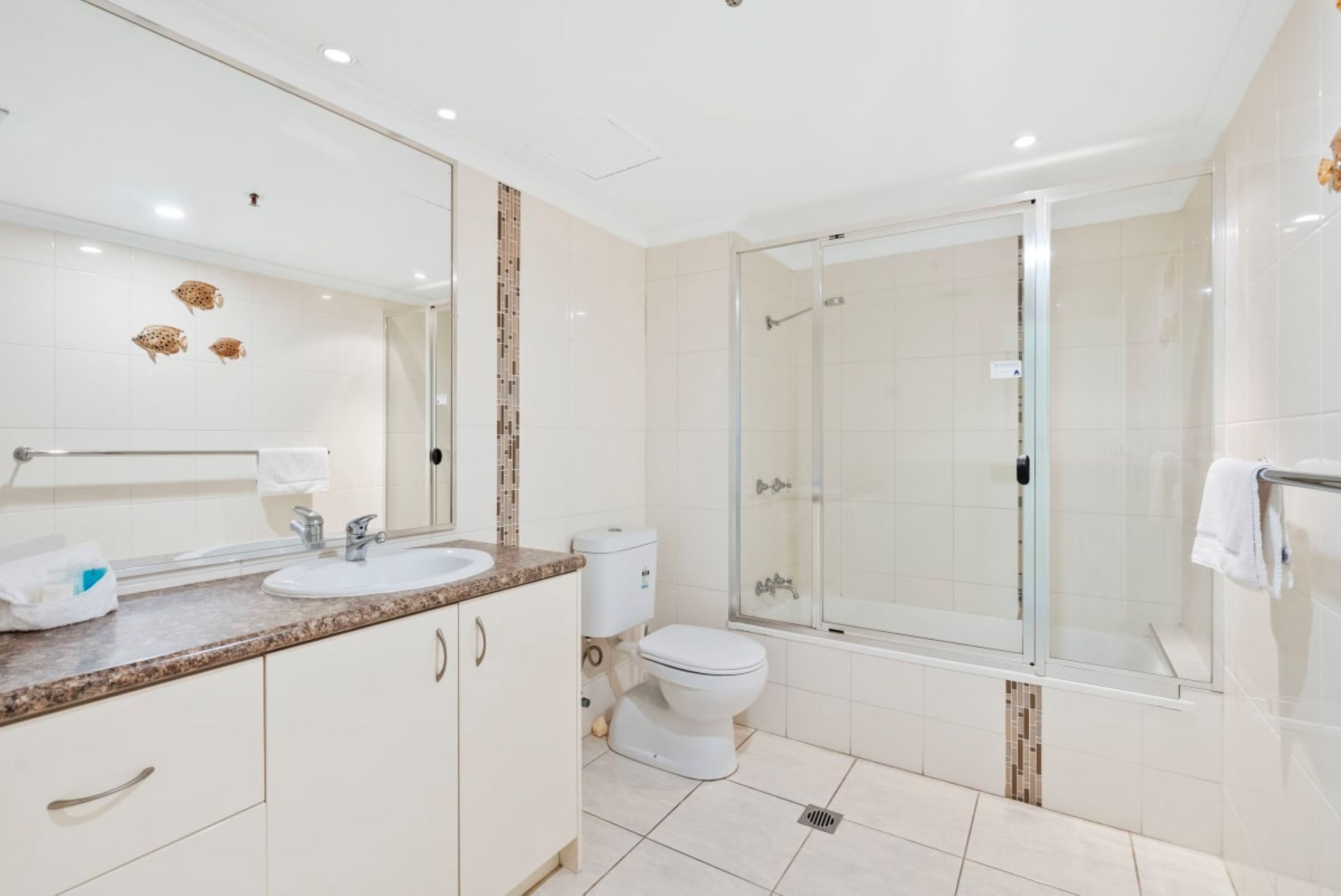 A modern bathroom with a glass-enclosed shower, a double sink vanity, and a toilet.