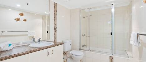 A modern bathroom with a glass-enclosed shower, a double sink vanity, and a toilet.