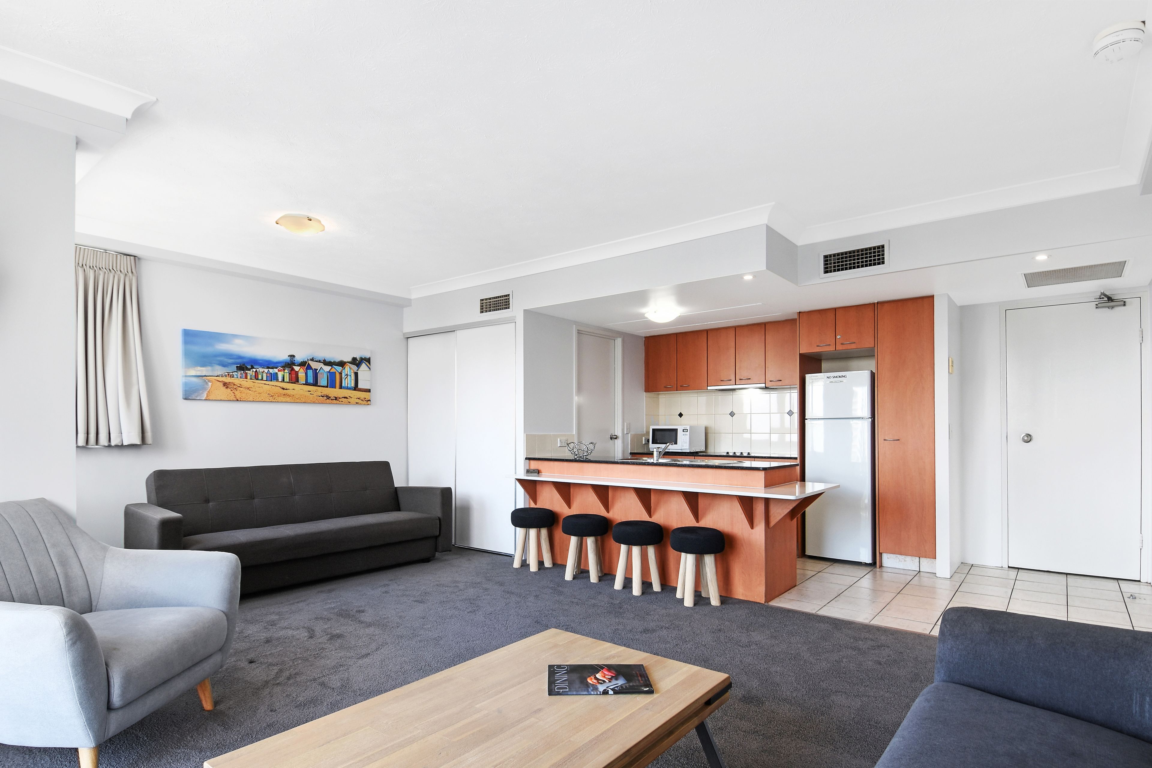 Een modern appartement met een woonkamer, een eetgedeelte met krukken en een kitchenette.