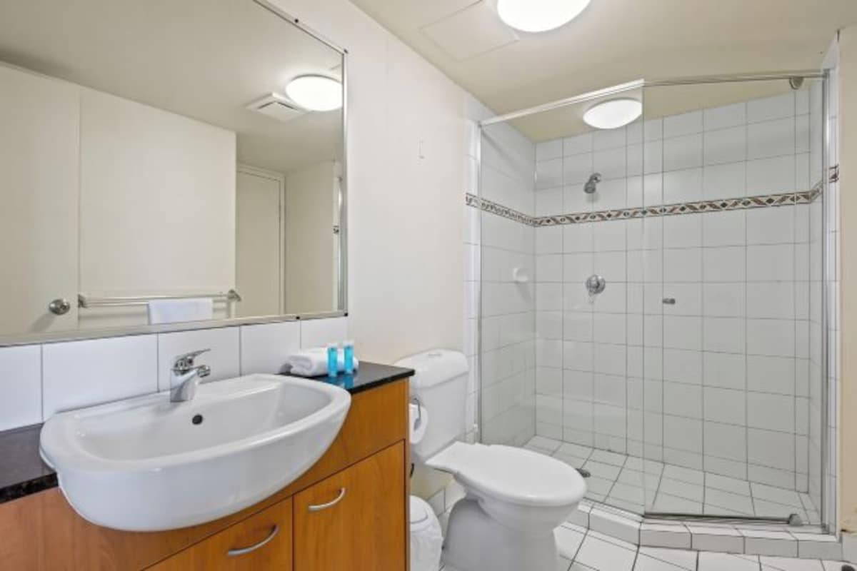 Une salle de bain comprenant un lavabo, un miroir, des toilettes et une douche séparée par des parois en verre.