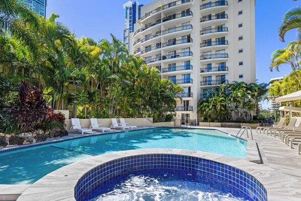 Una piscina al aire libre, sombrillas, sillones reclinables de piscina