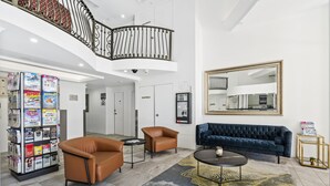 Un lobby moderno con una escalera, sillones de cuero, un sofá azul oscuro, una mesita de centro y un atril para revistas.