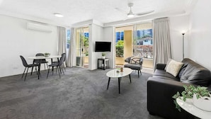 Una sala de estar moderna con sofá, mesa de centro, televisor y comedor.
