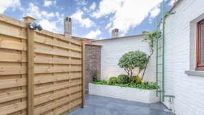 A courtyard with a wooden fence, a brick wall, and a white brick building. - Hotel Albert I (Bruges)