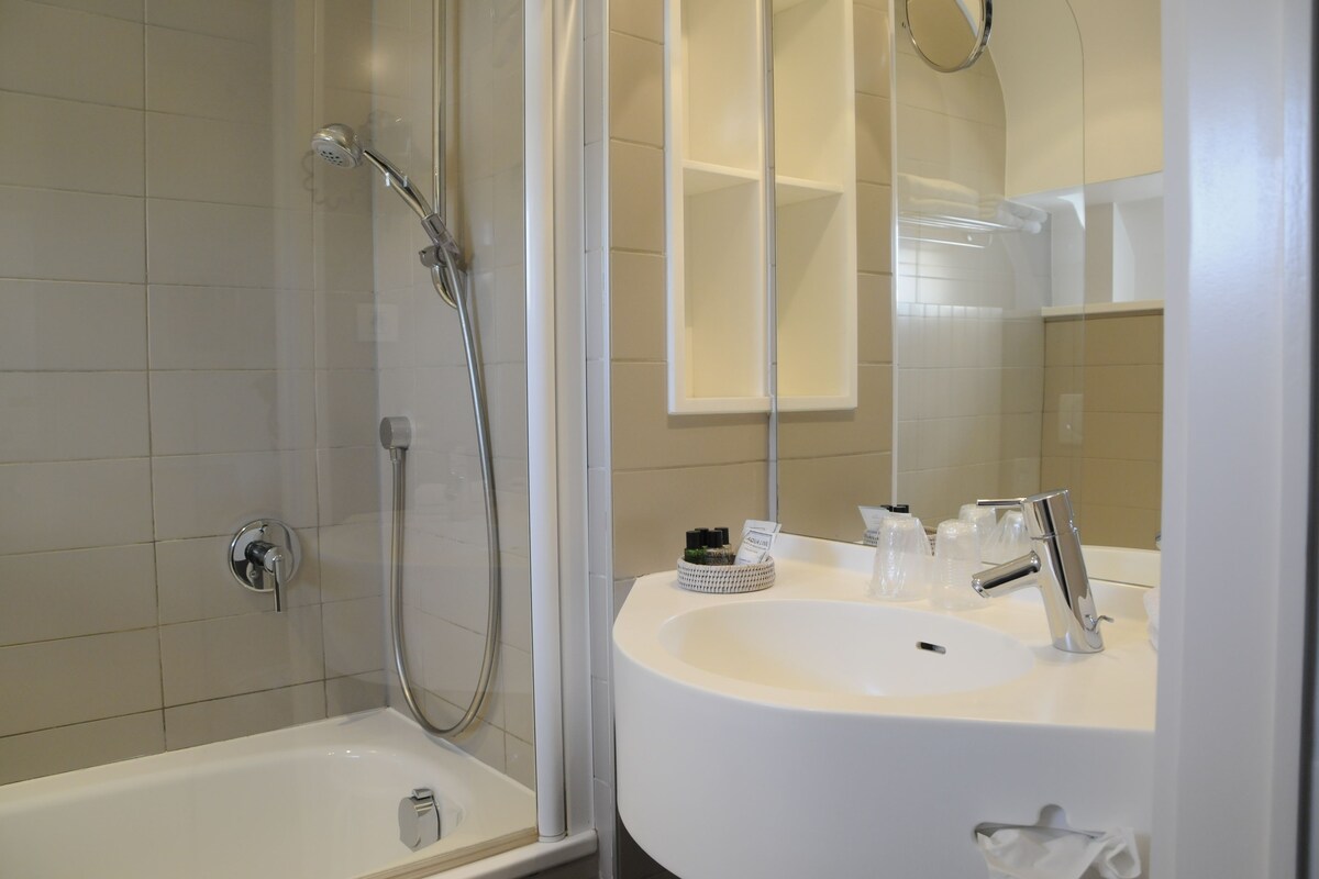 A modern bathroom with a bathtub, a shower, and a sink with a mirror above it.