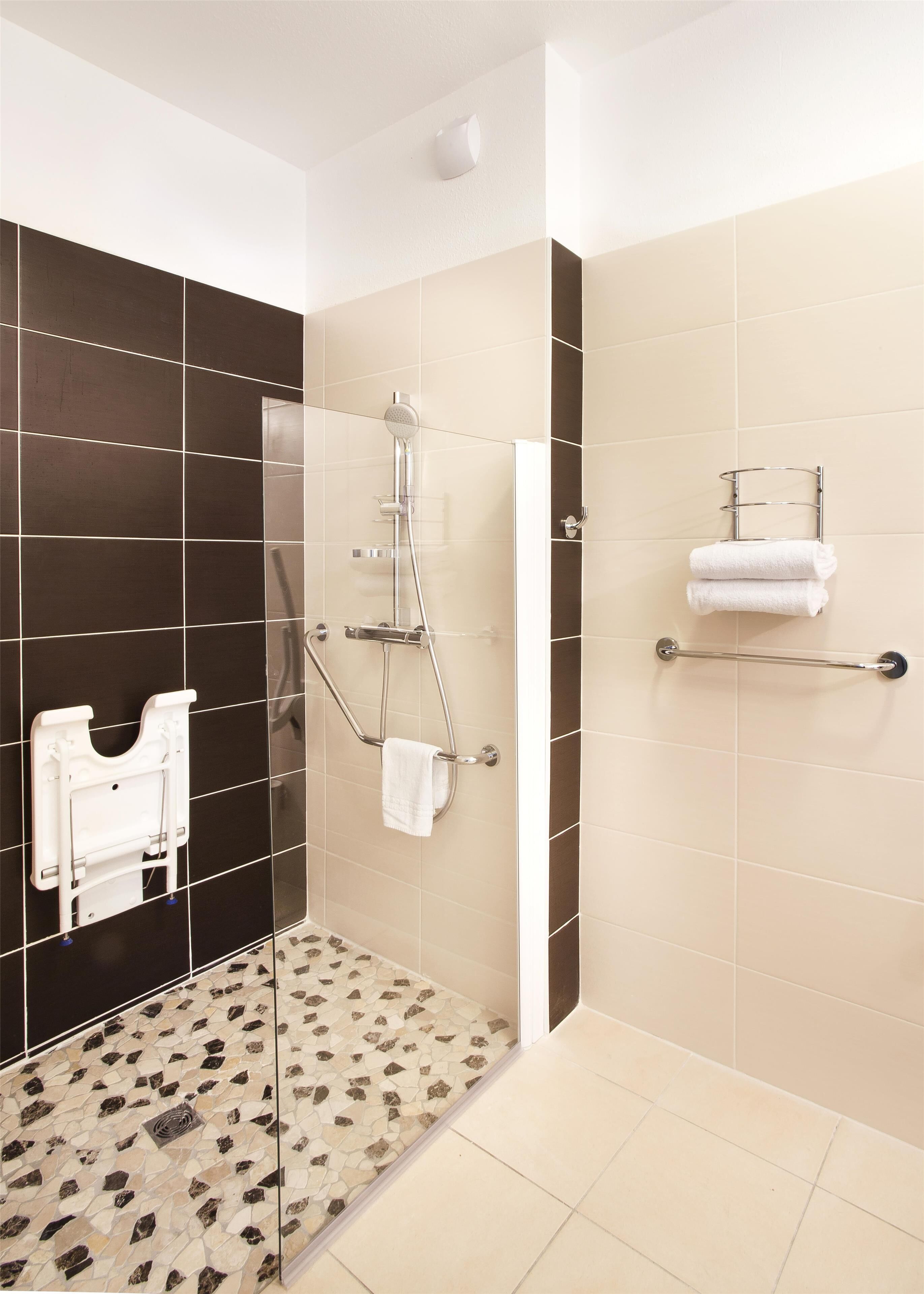 A modern bathroom with a shower, a toilet, and a towel rack.