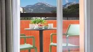 A balcony with a table set for dining, chairs, and a potted plant. - Kyriad Chambéry Centre - Curial (Chambery)