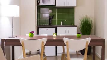 A compact living space with a kitchenette, a dining area with two chairs, a sofa, and a lamp.