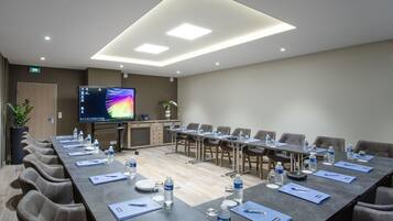 A conference room with a long table, chairs, water bottles, and a screen.