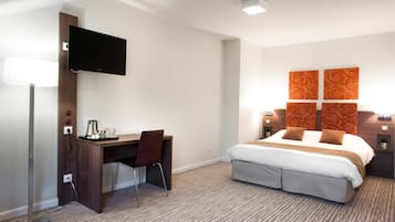 Une chambre d’hôtel équipée d’un lit, d’un bureau, d’une chaise, d’une télévision et de panneaux muraux décoratifs.