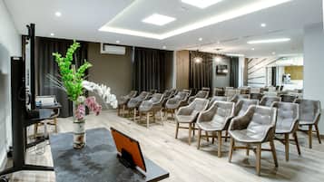 Una sala de conferencias con una larga mesa, múltiples sillas y una planta decorativa.