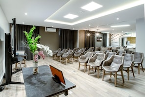 A conference room with a long table, multiple chairs, and a decorative plant.