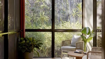 Une pièce dotée de grandes fenêtres en verre, de meubles en osier et de plantes en pot.