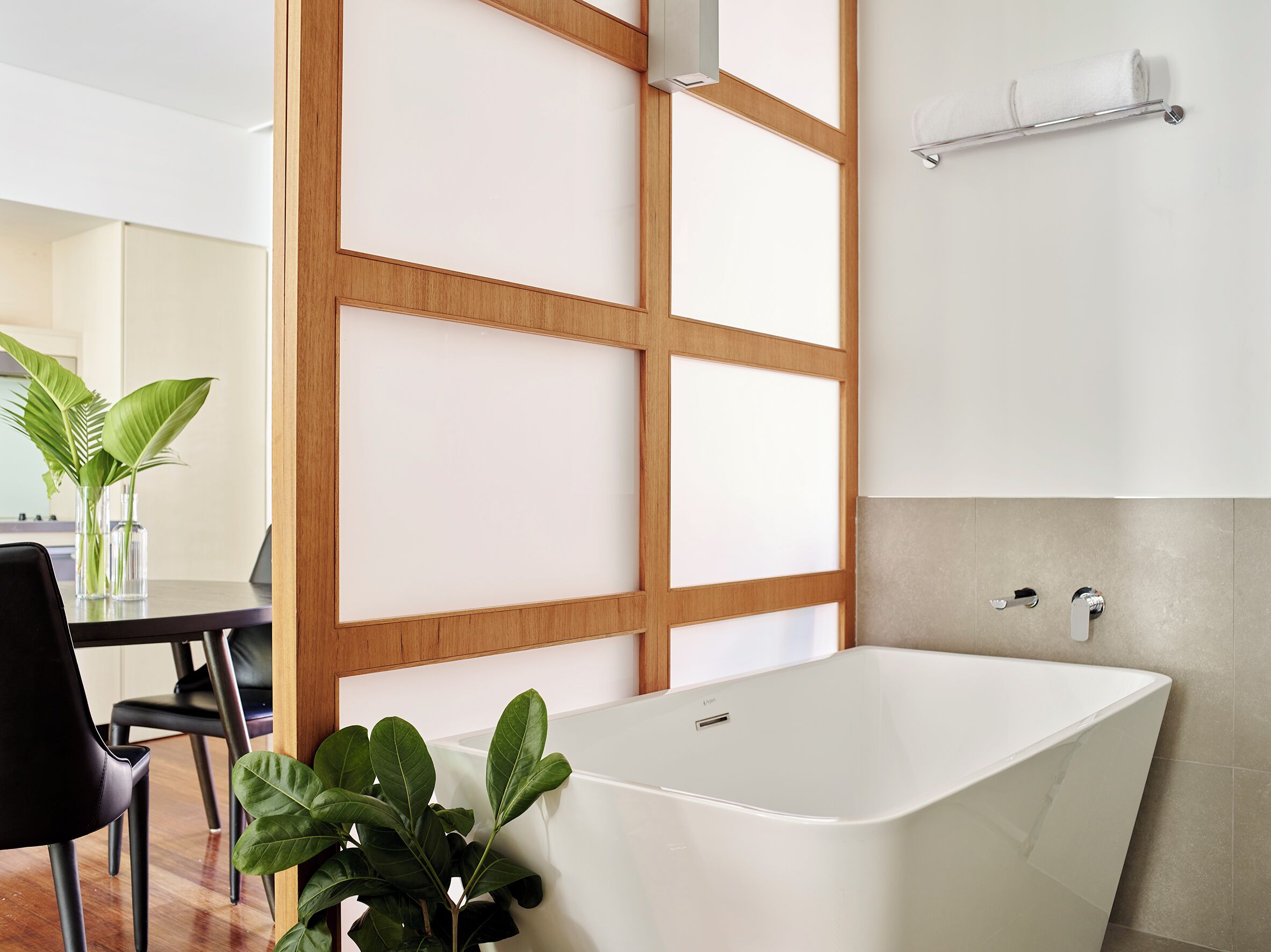Un baño moderno con una bañera independiente, separadores de madera y un perchero para toallas.