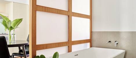 Un baño moderno con una bañera independiente, separadores de madera y un perchero para toallas.