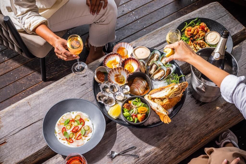 Et spisebord med fiske-retter, en champagneflaske og vinglas.