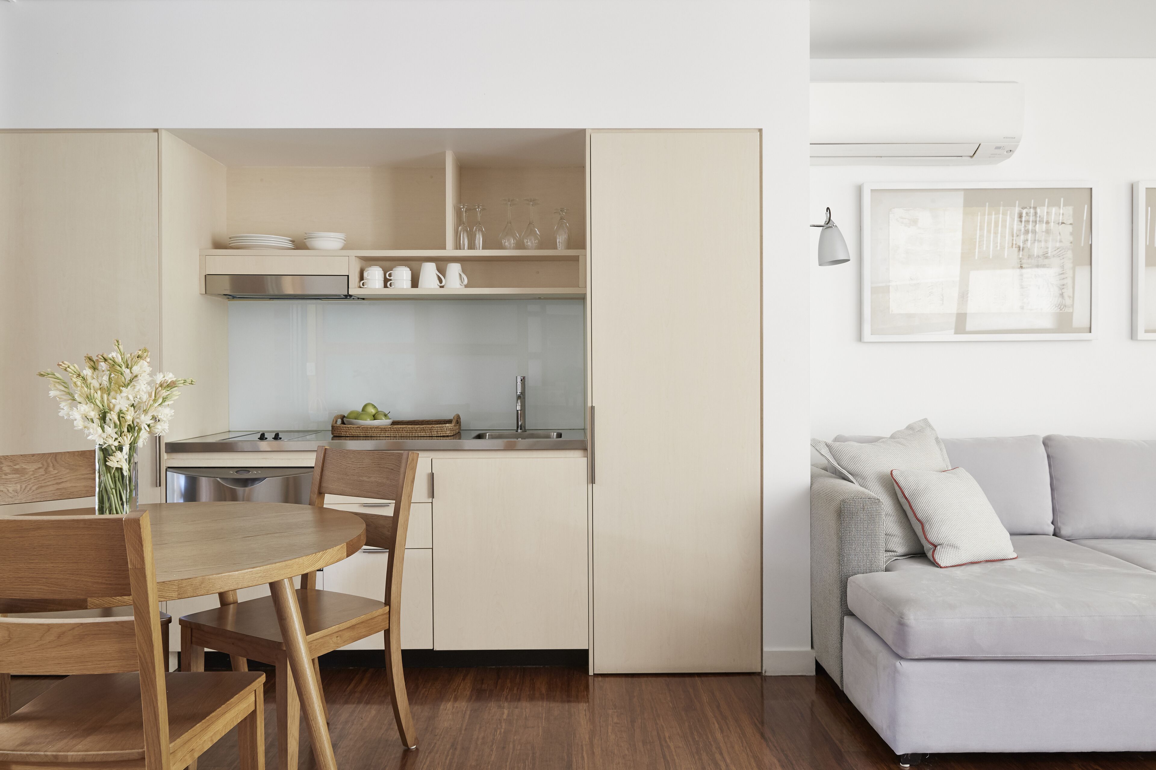 A modern kitchen with a dining area, a sofa, and a vase with flowers.