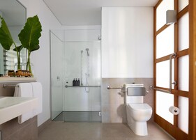 Un baño moderno con cabina de ducha de vidrio, un inodoro y un lavabo con toallero.