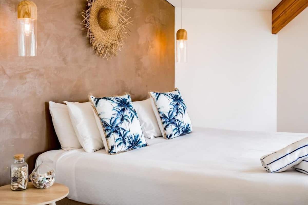 A bedroom with a bed, pillows, a wall-mounted hat, and pendant lights.