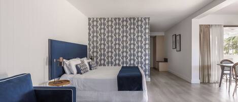 A modern bedroom with a large bed, a blue sofa, and a patterned wall.