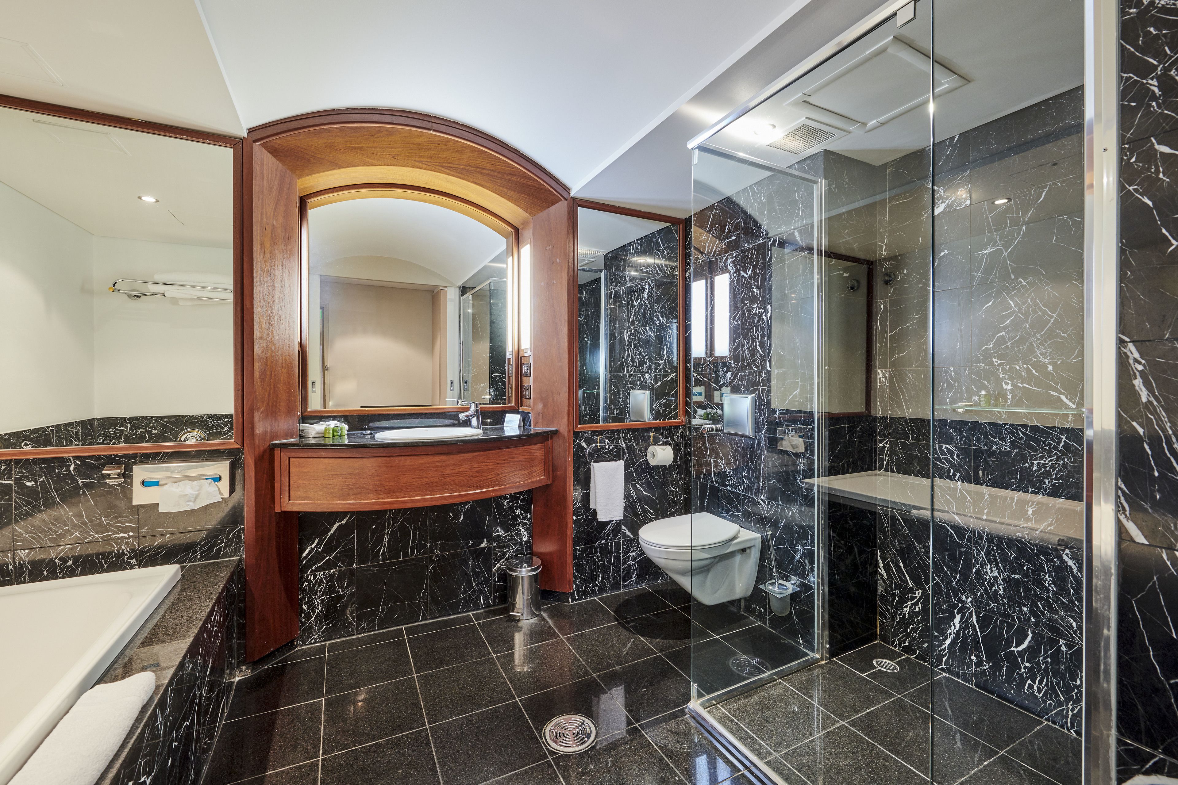 A modern bathroom with a marble vanity, a glass shower enclosure, and a separate toilet area.