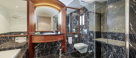 A modern bathroom with a marble vanity, a glass shower enclosure, and a separate toilet area.