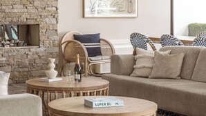 A cozy living room with a stone wall, a wooden coffee table, a beige sofa, and a wicker chair. - Waves Byron Bay (Byron Bay)
