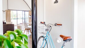 A room with a bicycle, a sofa, a dining table, and a large window. - Waves Byron Bay (Byron Bay)