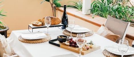 Una mesa puesta para una comida, con platos, cubiertos y una botella de vino.