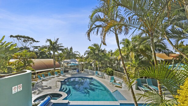 A swimming pool with lounge chairs and palm trees. - Lennox Beach Resort (Lennox Head)
