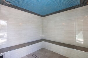 Uma casa de banho moderna com azulejos brancos, cabine de duche em vidro e teto azul.