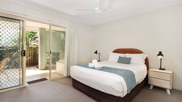 A bedroom with a bed, nightstands, a ceiling fan, and a sliding glass door leading to an outdoor area.