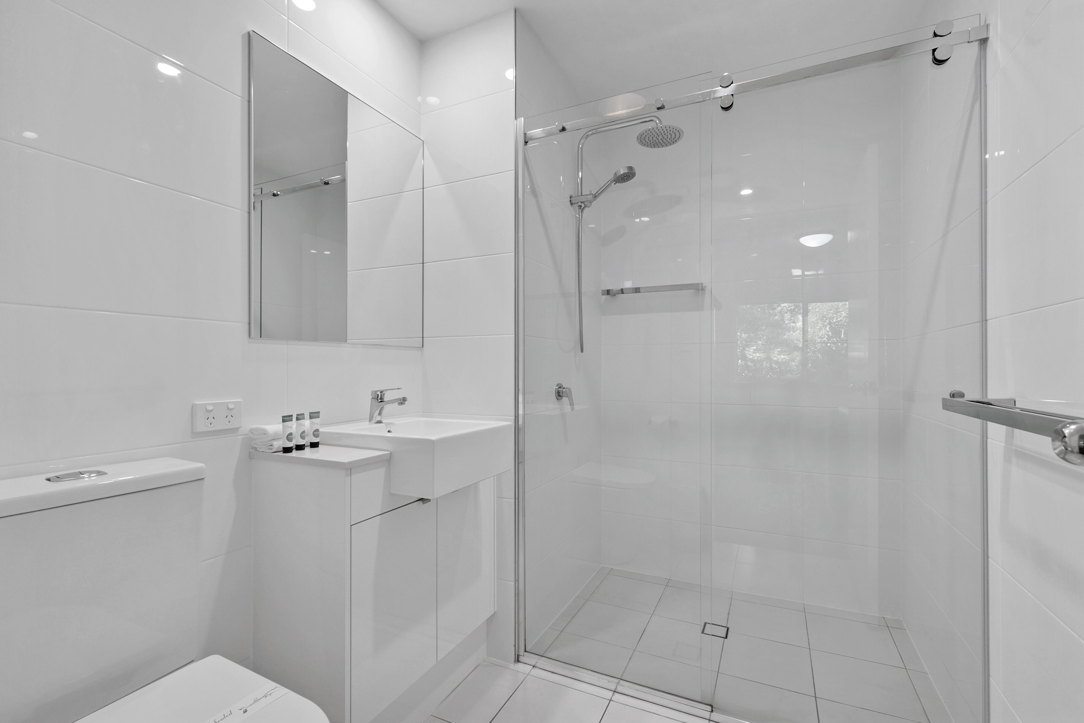 A modern bathroom with a glass-enclosed shower, a sink, and a toilet.