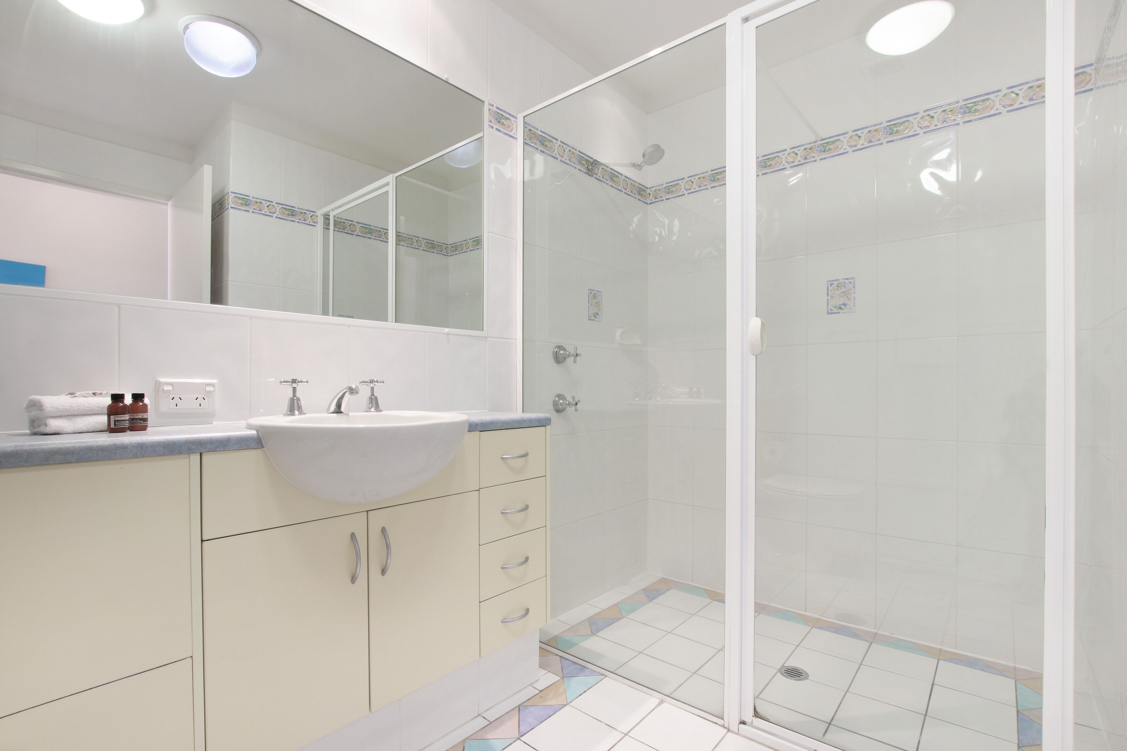 A bathroom with a sink, mirror, and shower.