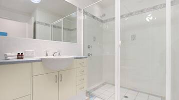 A bathroom with a sink, mirror, and shower.