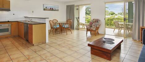 A modern kitchen with a dining area, a wooden table, and a balcony with outdoor seating.