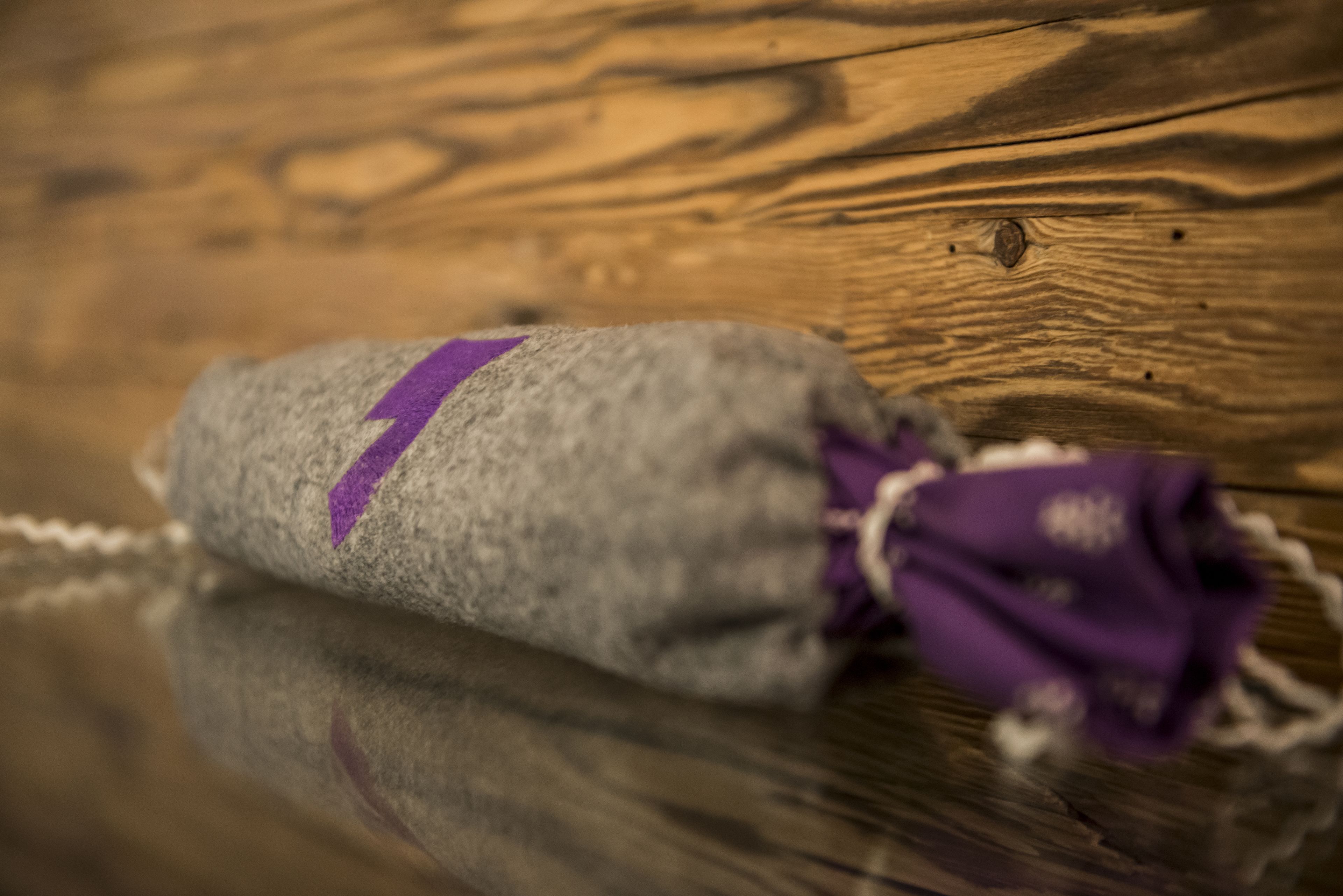A small, rolled-up item with a purple stripe on a wooden surface.
