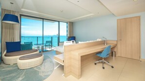 A modern hotel room with a large balcony, a wooden desk, a comfortable seating area, and a view of the sea. - Holiday Inn Pattaya by IHG (Pattaya)