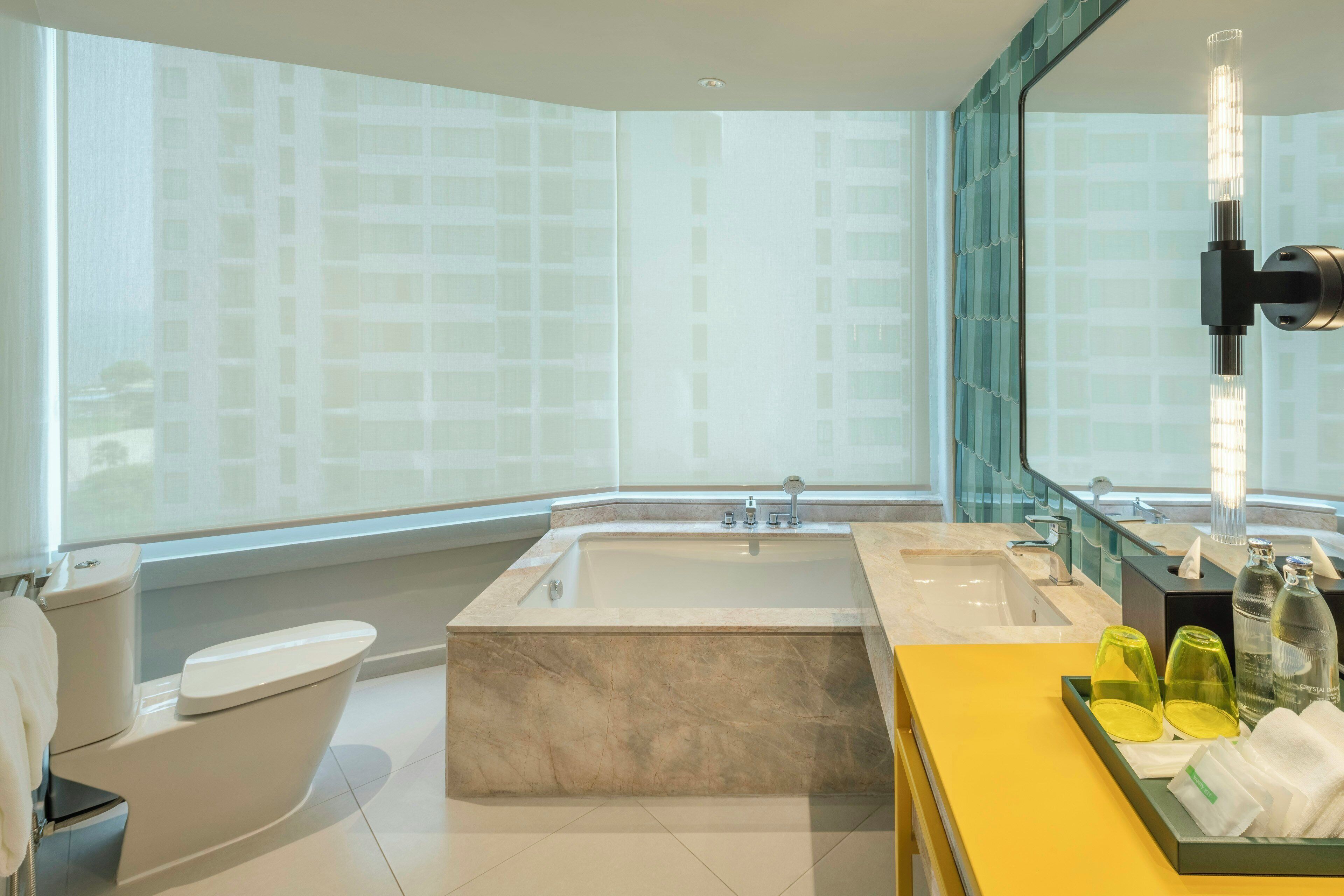 Une salle de bain moderne équipée d’une baignoire, de toilettes, d’un lavabo et d’un meuble-lavabo avec des articles de toilette.
