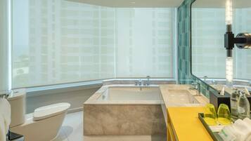 A modern bathroom with a bathtub, a toilet, a sink, and a vanity with toiletries.