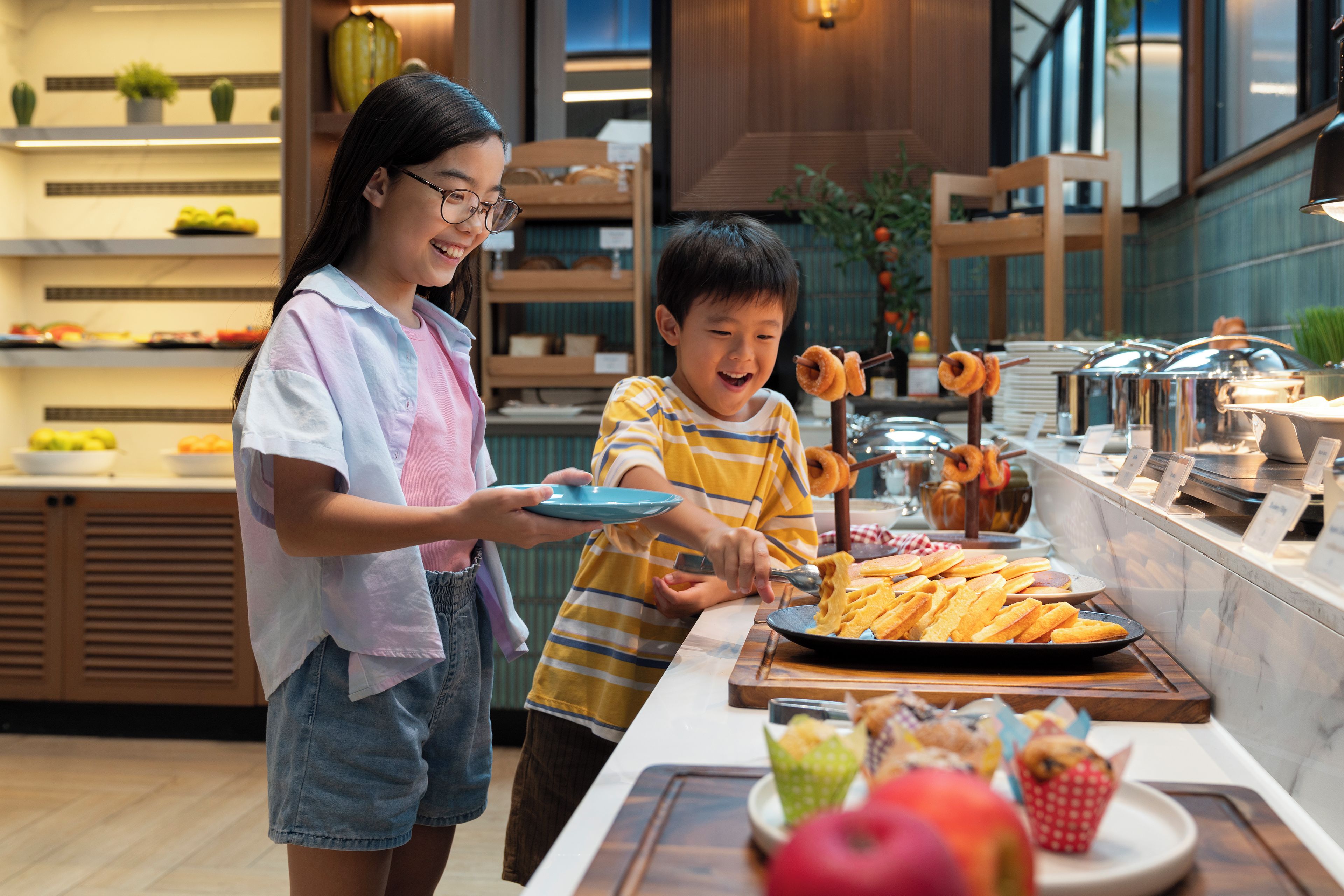A modern kitchen with a buffet setup, including a variety of food items and a child serving himself.