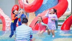 Children playing in a water park with large red slides and a water fountain. - Holiday Inn Pattaya by IHG (Pattaya)