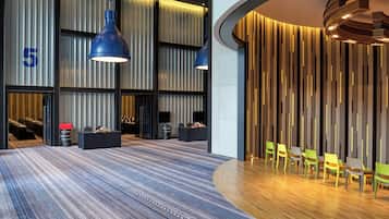 A modern hotel lobby with a striped carpet, a reception desk, and a seating area with chairs.