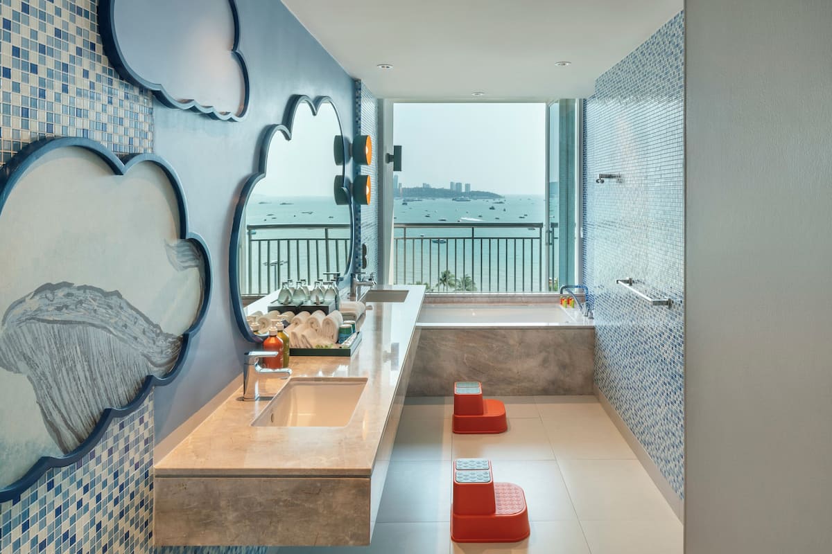 Un baño moderno con un ventanal grande, un lavamanos y una bañera.