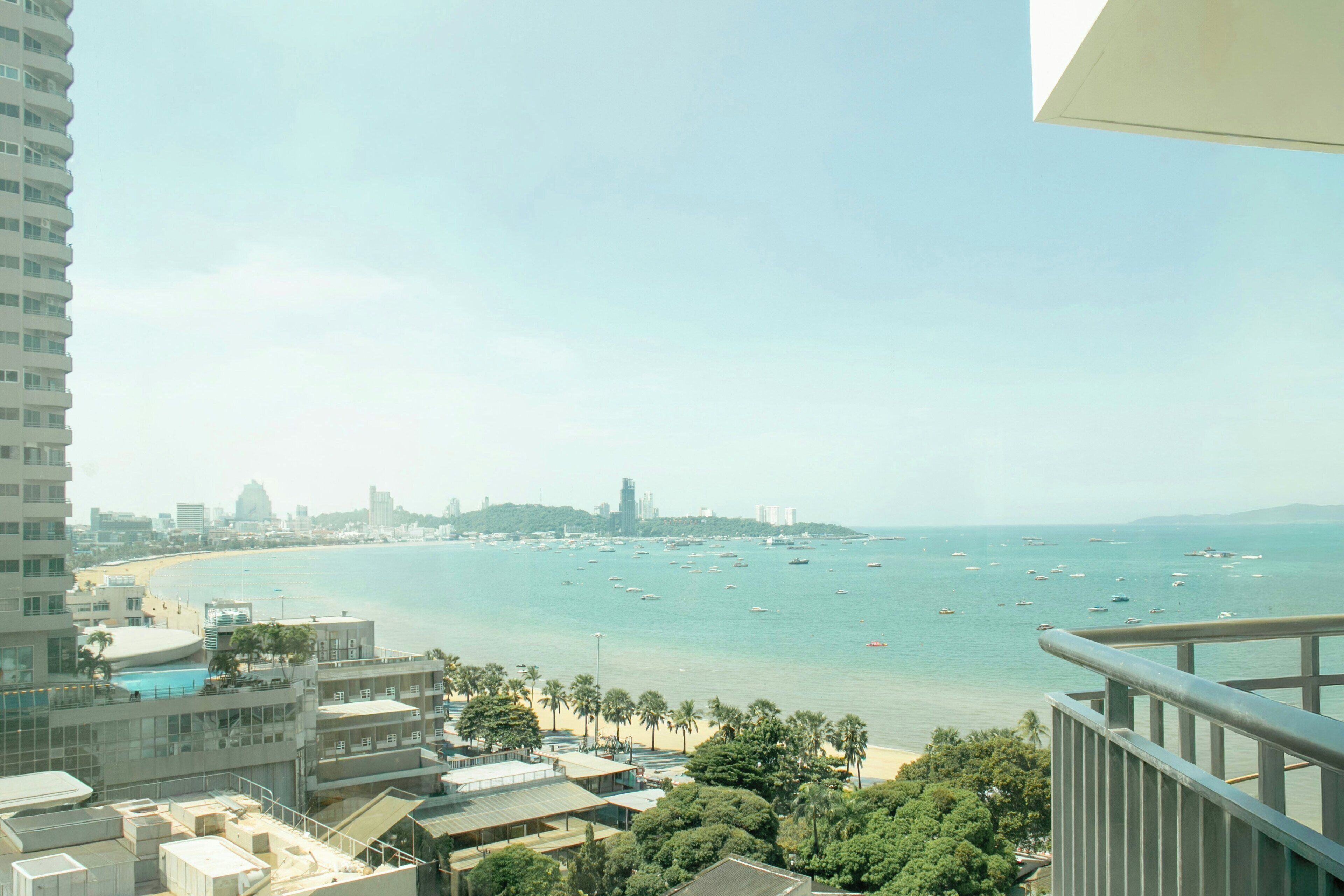 A coastal cityscape with a view of the sea, buildings, and a clear sky.