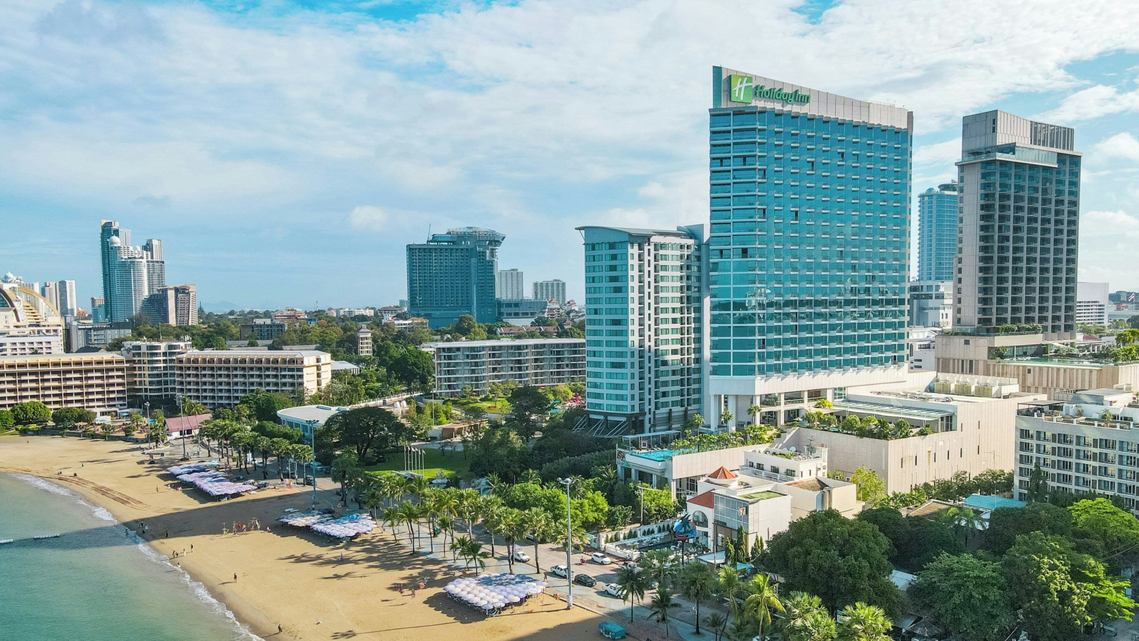 A beachfront hotel with multiple high-rise buildings, a sandy beach, and a clear sky.